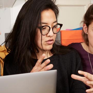 Young people huddled round a laptop