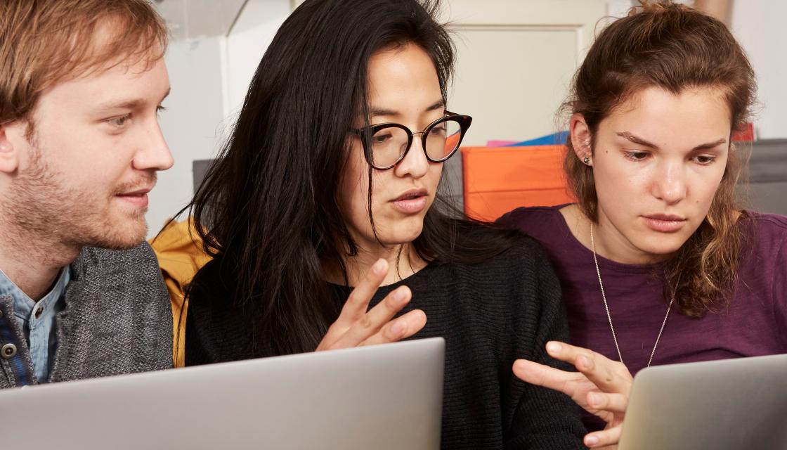 Young people huddled round a laptop